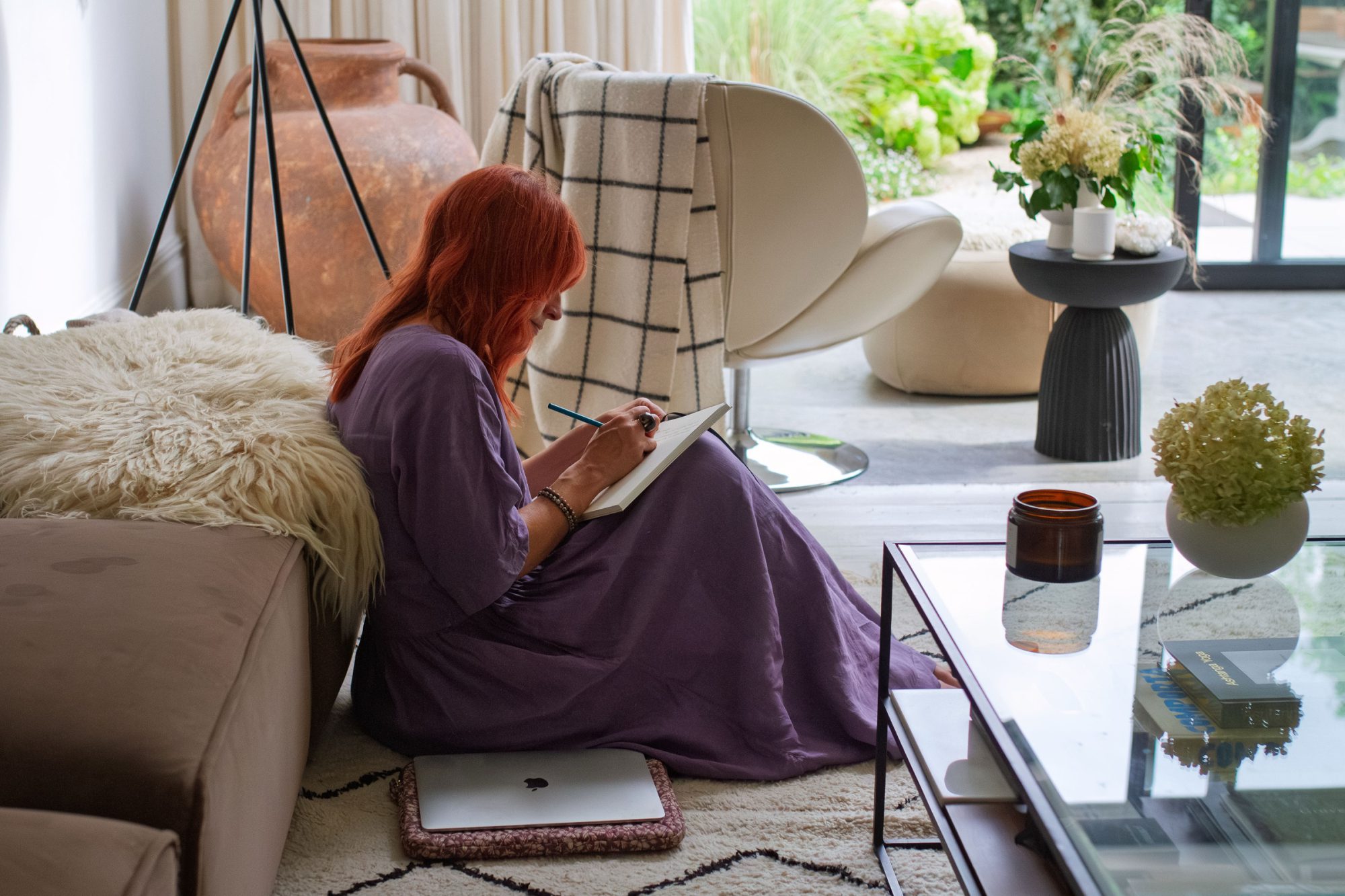 Nicola writing in a notebook, sitting on the floor of her living room